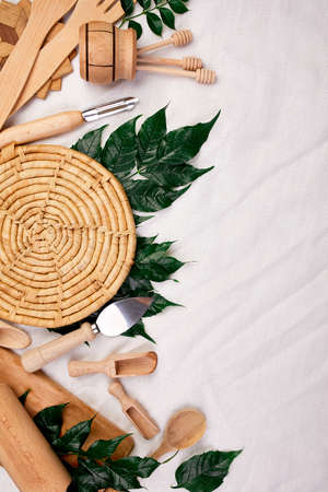 Flat lay with wooden kitchen utensils with green leaves, cooking tools on textile background, cooking blogs and classes concept, ktchenware collection captured from above, mockup, frame.の写真素材