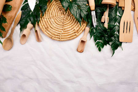 Flat lay with wooden kitchen utensils with green leaves, cooking tools on textile background, cooking blogs and classes concept, ktchenware collection captured from above, mockup, frame.の写真素材