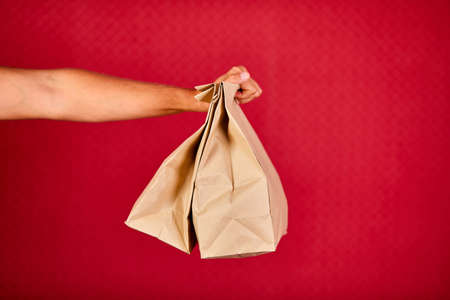 Closeup courier hand holding grocery paper bag, delivery service