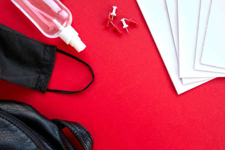 School supplies, protective mask and antiseptic on a red background
