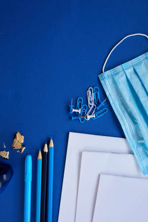 School supplies, protective mask and antiseptic on a blue background
