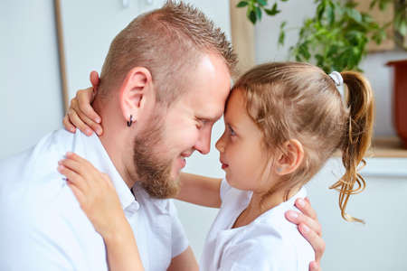 Adorable little girl in white dress hugging loving fatherの写真素材