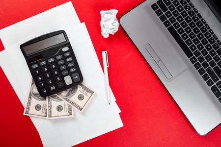 Flat lay with workspace on red backgroud, freelancer online, financial concept, make money on the Internet, dollars, calculater, notebook, concept of search idea.の写真素材