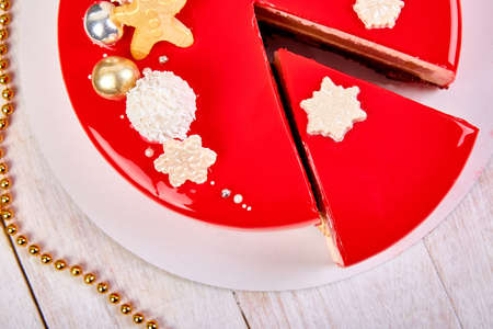 Top view Mousse Christmas pastry cake dessert covered with red mirror glaze with new year decorations on white background, Modern european cake Christmas theme.の写真素材