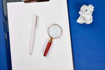 Flat lay of concept of search idea, goals, Business image, Magnifying glass and crumpled paper on blue background, Finding the best idea and inspiration among others, Search Engine Marketing.の写真素材