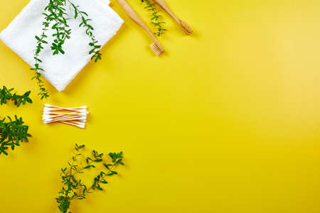 Bamboo toothbrushes and ear sticks with towel, and green leaves on yellow paper background, Eco-friendly, Zero waste personal hygiene products, dental care conceptの写真素材