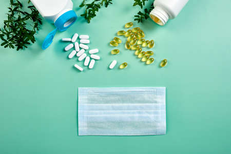 Flat lay of Medical face mask and pills, fish oil, vitamins on blue backgroundの写真素材