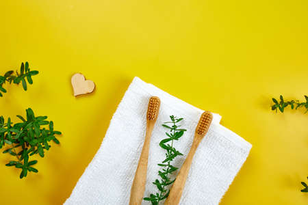 Bamboo toothbrushes and ear sticks, and green leaves on yellow paper background, Eco-friendly, Zero waste personal hygiene products, dental care conceptの写真素材