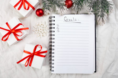 Top view of blank notebook for goals resolutions and christmas decoration on white textile linen...
