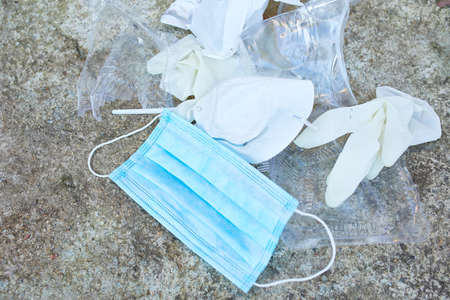 A globe in a pile of scattered garbage on road background , Around scattered plastic, protective mask, gloves, waste during pandemic. Save the World.の写真素材