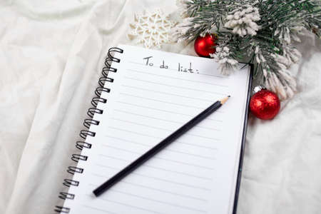 Top view of blank notebook for to do list and christmas decoration on white textile linen tablecloth background, flat lay, copy space, new normal year.の写真素材