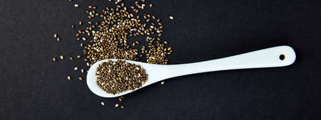 Banner of Chia in white spoon on black background. Copy space. Flat lay.の写真素材