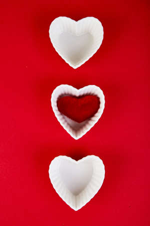 White ceramic hearts with red plush  hearts on red background. Flat lay composition. Romantic, St...