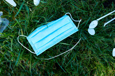 Piile of scattered garbage on a background of green grass, Around scattered plastic, protective mask, gloves, waste during pandemic, Save the World.の写真素材