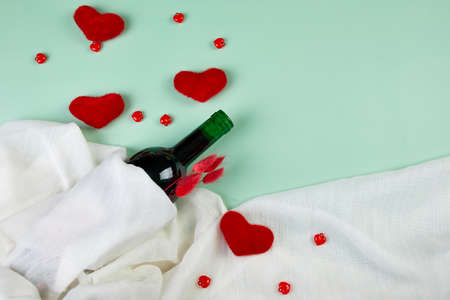 Flat lay of Valentines day greeting card with red wine bottle and hearts on blue background. Top view with copy space, Romantic greeting card.の写真素材