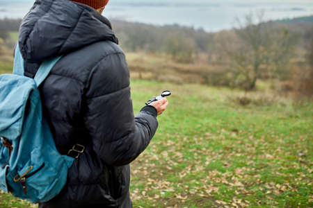 Traveler man with backpack with compass in hand on a background of mountains river of nature, Travel...