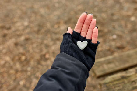 Traveler girl in black gloves keep in hand marshmallow in shaped heart, love, valentine day, outdoor, copy space.の写真素材