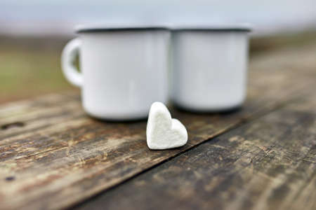 Enameled Two cups of tea in nature on wooden background, love, heart of marshmallow, travel concept, Lifestyle moment at nature, Valentine day, copy space.の写真素材