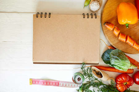 Flat lay of various organic vegetables ingredients and measuring tape on wooden background, Vegetarian and vegan food, diet spring concept, top view, copy space.の写真素材