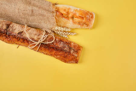 Top view of two baguette bread on a yellow surface.  Concept of homemade bread, small bakery,...