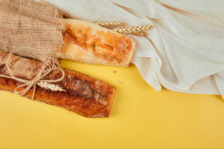 Top view of two baguette bread on a yellow surface.  Concept of homemade bread, small bakery, natural farm products, local food,  domestic production. Healthy and tasty organic food. Copy space.の写真素材