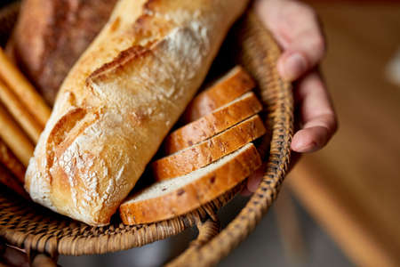 Close yp of man hand, holding basket with various bread freshly baked. Close up concept of homemade bread, small bakery, natural farm products, local food, domestic production. Healthy and tasty organic food.の写真素材