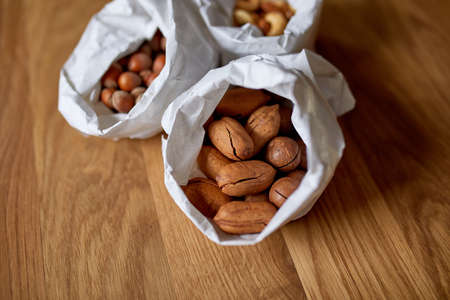 Top view Various sort of nuts on the table in a paper bag on wooden background, shopping grocery concept, nuts delivary, Zero Waste Food Shopping. Copy space.の写真素材