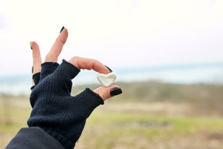 Traveler girl in black gloves keep in hand marshmallow in shaped heart, love, valentine day, outdoor, copy space.の写真素材