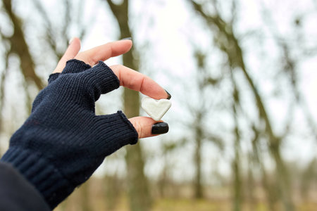 Traveler girl in black gloves keep in hand marshmallow in shaped heart, love, valentine day, outdoor, copy space.の写真素材
