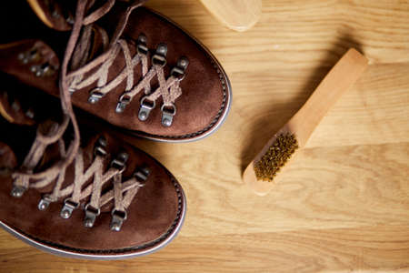 Flat lay, top view footwear with suede shoe boots care accessories, brush on wooden table. Footwear maintenance captured, copy space, for text.の写真素材