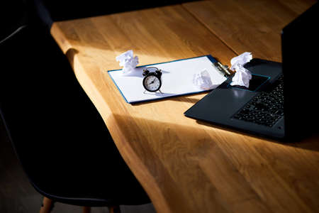 Modern workplace, wooden office desk in hardlight, sunligt with clock, sheet of paper, laptop,...