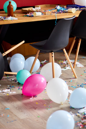 After party chaos, messy in livving room at home, table with pizza and champagne glasses covered...