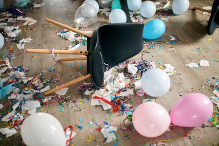 After party chaos, messy in livving room at home, table with pizza and champagne glasses covered...
