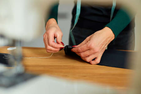 Step by step, 50-yers old woman sewing fabric with hand, Mature tailor working with sewing in atelier, textile industry, hobby, workspace. Creation process DIY, Workplace of seamstress.の写真素材