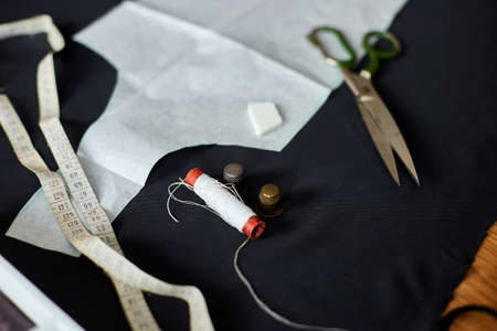 Top view of Sewing supplies on a wooden table: sewing thread, scissors, pieces of cloth, needles,...