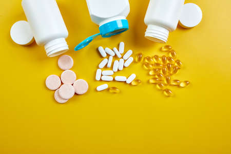 Flat lay of pills, fish oil, vitamins with green leavws on yellow background, Healthcare concept, healthy food, supplements for healthy good life, Immune booster.の写真素材