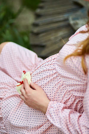Unrecognizable pregnant woman touching belly, waiting for a miracle, Pregnant tummy close up, outdoor in spring or summer parkの写真素材