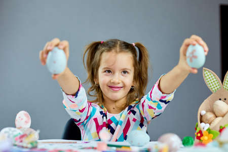 Cute little child girl on Easter day hold easter egg in hand at home. Girl with painted eggs on...