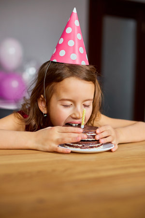 A little girl is wearing a birthday tasty, eat a Birthday Cake for a celebration party concept.の写真素材