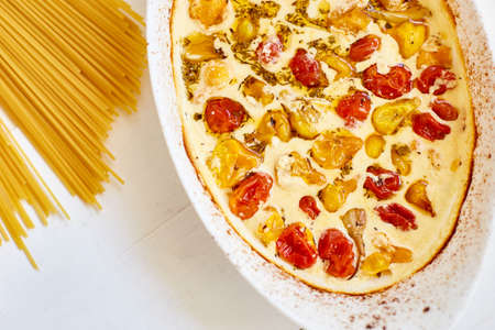 Trending viral recipe of baked tomatoes and feta with pasta, Fetapasta on a white wooden background. New, popular dinner dish, Top view, copy space.の写真素材