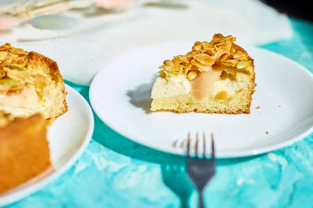 Piece of apple or pear pie, tart with caramel nuts on blue table with sunlight, copy space, top...