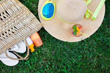 Flat lay of outdoor bright summer beach vacation or travel lifestyle concept  with straw bag, hat,...