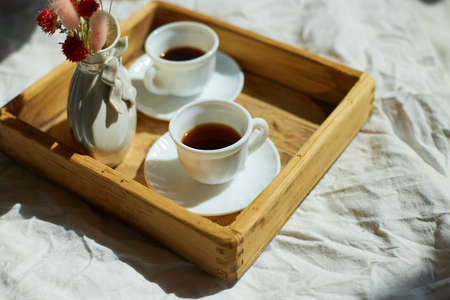 Breakfast in bed, try with two cups coffee and flower in sunlight at home, chambermaid bringing tray...