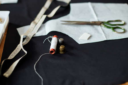 Top view of Sewing supplies on a wooden table: sewing thread, scissors, pieces of cloth, needles, centimeter, pattern.の写真素材
