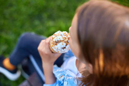 Unrecognizable girl with italian ice cream cone in hand,  resting in park on summer day, child enjoying ice cream outdoor, happy holidays, summertimeの写真素材