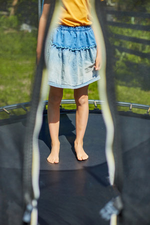 Leg of little child jumping on trampoline in the backyard of the house on a sunny summer day, summertime vacation.の写真素材