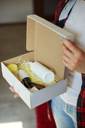 Brunette woman opening, hold in hand online order parcel box with cosmetics at home, Female customer...