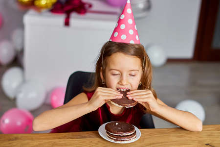 A little girl is wearing a birthday tasty, eat a Birthday Cake for a celebration party concept.