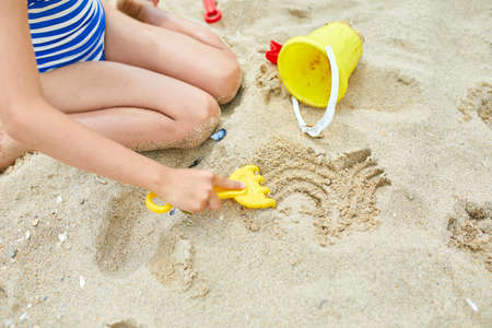Little girl kid having fun on the beach and playing with sand toys, family summer vacation, Background with empty space for textの写真素材