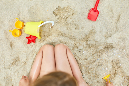 Top view of Little girl kid having fun on the beach and playing with sand toys, family summer vacation, Background with empty space for textの写真素材